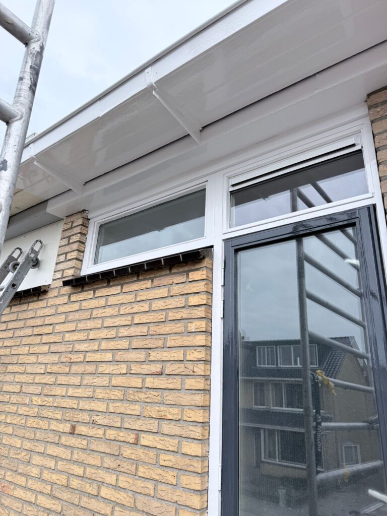 Buitenmuur met witgeschilderde dakrand en raam