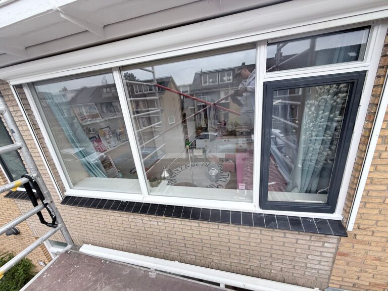 Man reinigt ramen op steiger.