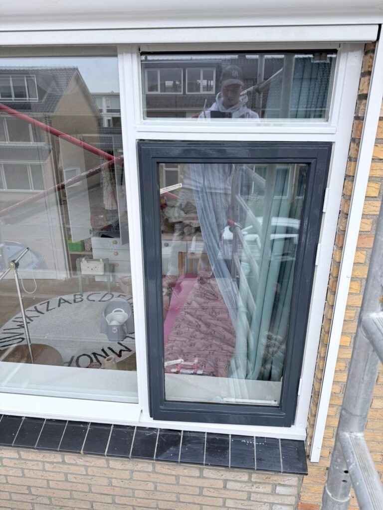 Grote glas-in-lood raam in een huisgevel.