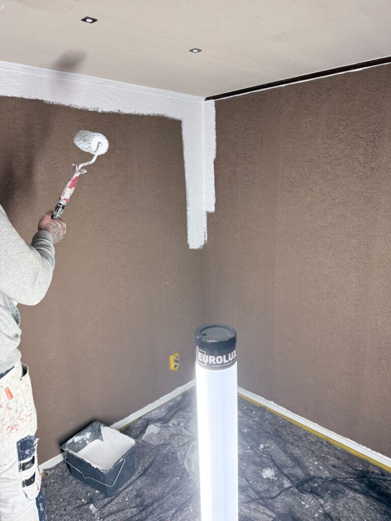 Schilder wit muur met verfroller in kamerhoek.