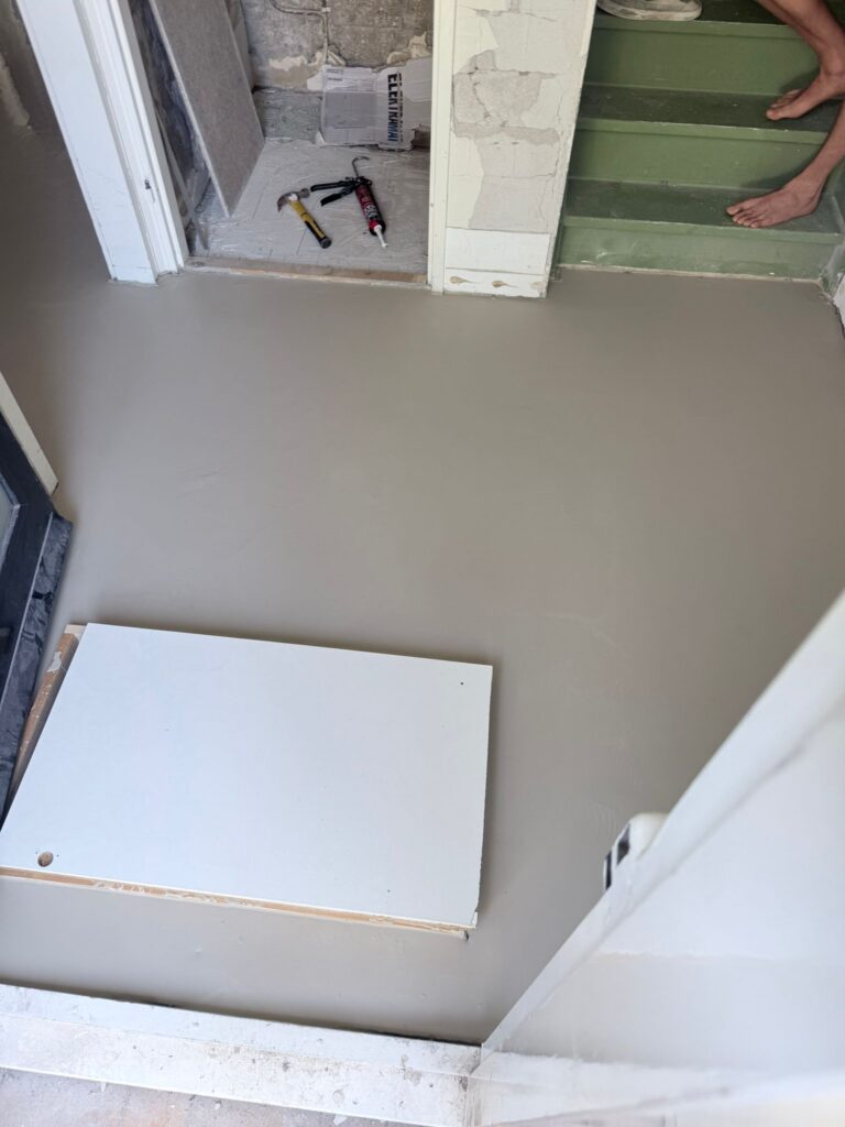 Nieuw gestorte betonnen vloer in renovatieruimte.