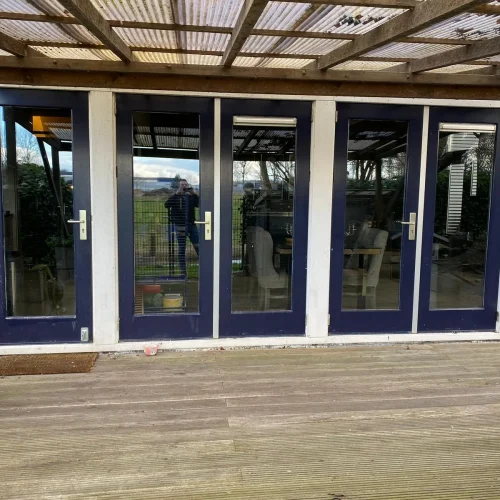 Donkerblauw gelakte tuindeuren en kozijnen onder een houten pergola in Castricum